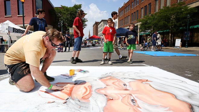 Erik Greenawalt, of Pittsburgh, blends chalk on his drawing of Mark Twain during the 2015 Elmira Street Painting Festival.
