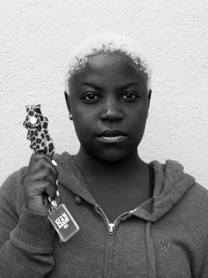 Des Moines native Breona Carroll held up a can of mace for her portrait in the “Guarded” series.