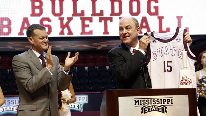 Ben Howland holds up a school basketball jersey while Athletic Director Scott Strickland applauds after introducing Howland as Mississippi State's new men's basketball coach Tuesday afternoon, March 24, 2015 on the floor at Humphrey Coliseum on the school's campus in Starkville, Miss.