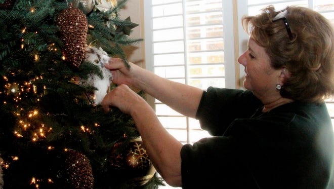 A member of the Carlsbad Assistance League places decorations in a tree featured in the home of Cheri Panzer for the 2015 Home Tour.