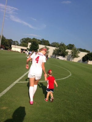 Ole Miss soccer player Sara Coleman walks her daughter, Parker, off the field.
