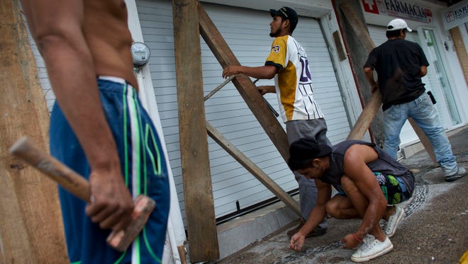 Men remove protective wood beams from the front of a business the morning after Hurricane Patricia passed further south sparing Puerto Vallarta, Mexico, on Oct. 24, 2015.