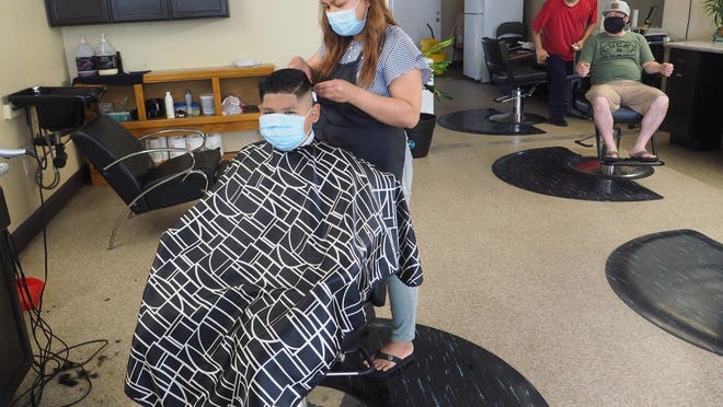Kanika Loch, 43, cuts 11-year-old Santiago Ceya's hair in June at Salon & Barber on Stockton's East Alpine Avenue. Though the state gave the go-ahead for barber shops and nail salons to open if they provide services outdoors this week, for many salon and barbershop owners, it's not that easy.