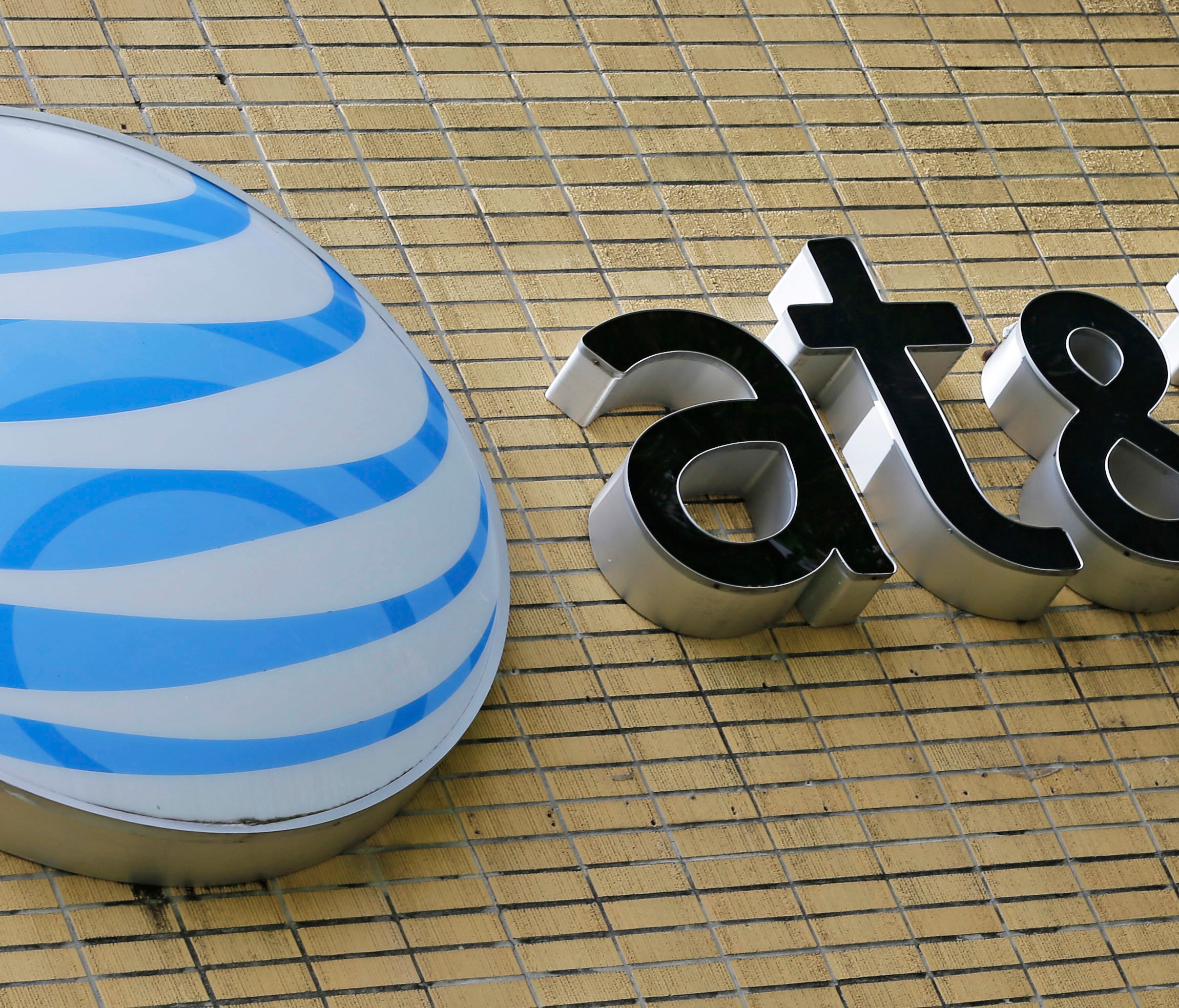 Bonus Time: File photo shows an AT&T sign at a store in Miami. The telecom company says it will pay bonuses and boost pay for workers once President Trump signs the tax bill passed by Congress into law.