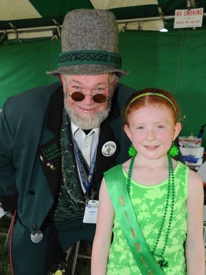 Liam, the world’s largest leprechaun, stands with Brooklynne McLaren of Redford, the winner of the person with the reddest hair at the Irish Fest held this past weekend in Redford.