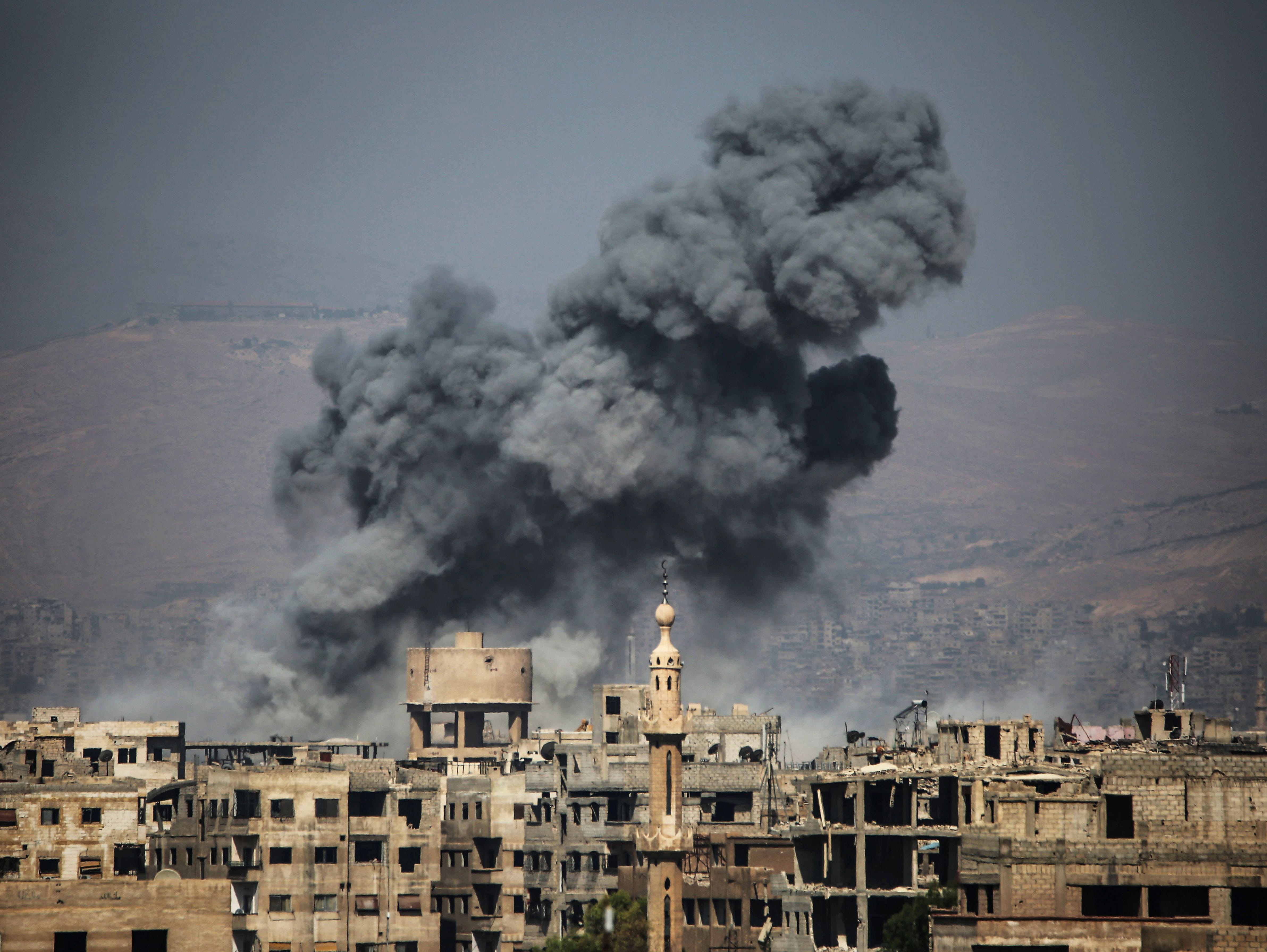 Smoke rises from buildings following a reported airstrike on the rebel-held town of Ayn Tarma, in Syria's eastern Ghouta area, on July 7, 2017.