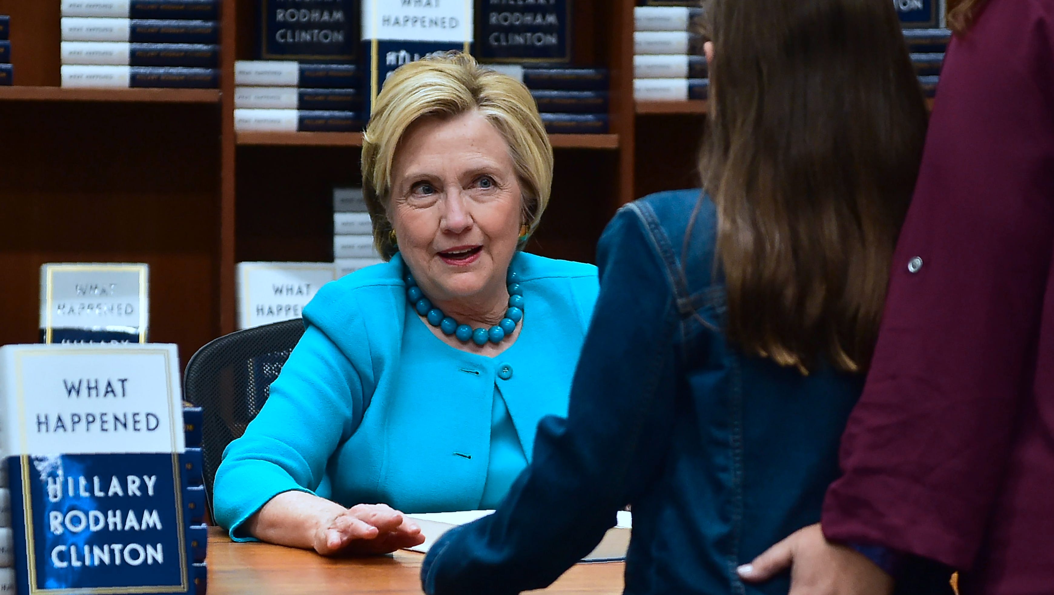 Hillary Clinton greets a supporter getting a signed copy of Clinton