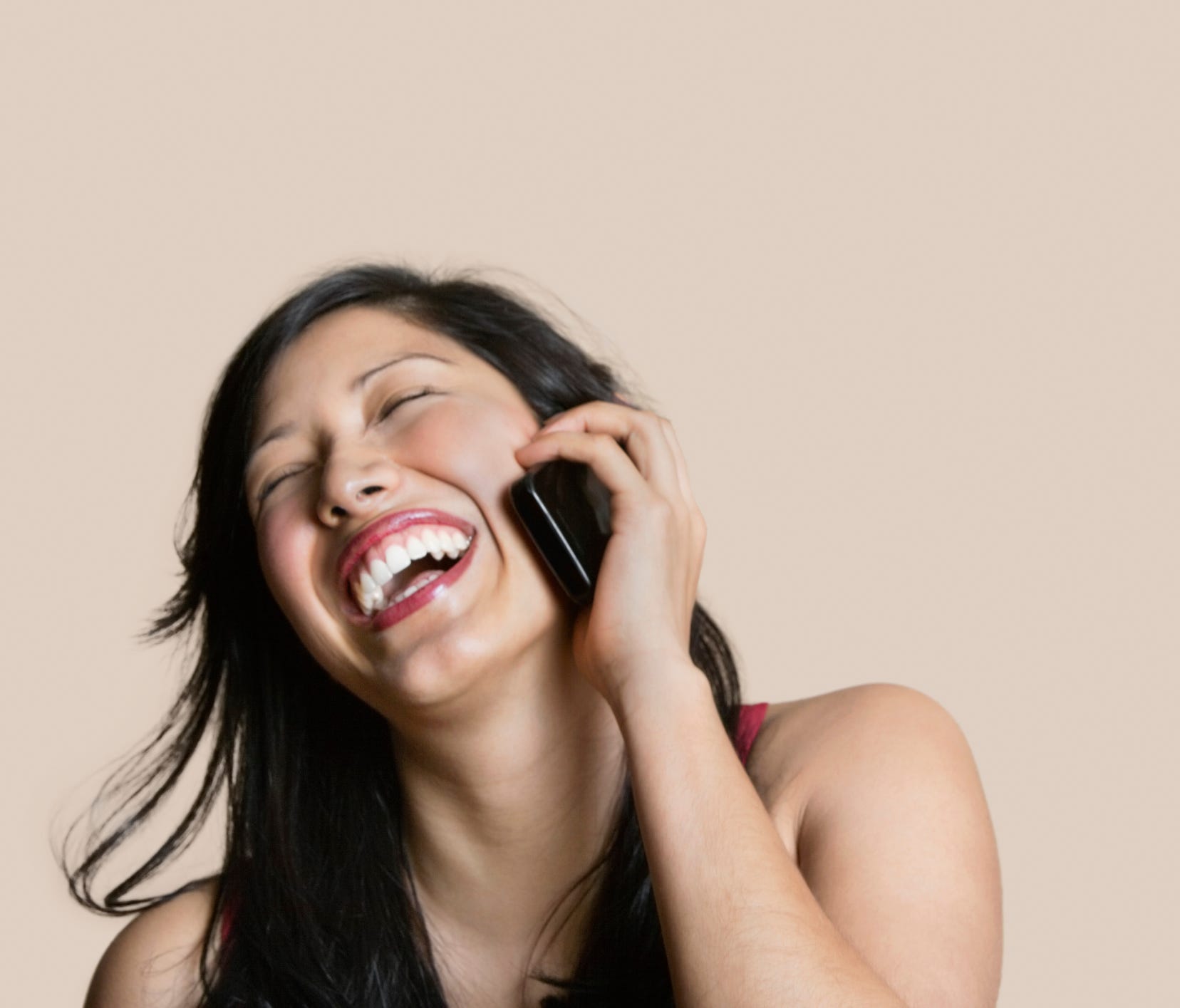 Cheerful young woman talking on mobile phone over colored background.