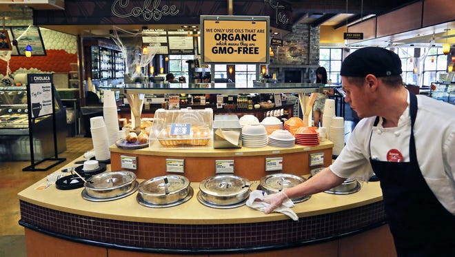 FILE - In this Oct. 23, 2014 file photo, a grocery store employee wipes down a soup bar with a display informing customers of organic, GMO-free oils, in Boulder, Colo. Food companies are mounting an aggressive year-end push to head off mandatory labeling of genetically modified foods. The food industry wants the labeling to be voluntary, and it hopes to get a provision in a massive spending bill that Republicans and Democrats want to wrap up this week. If that occurs, companies would not be forced to disclose whether their products contain genetically modified organisms, or GMOs.