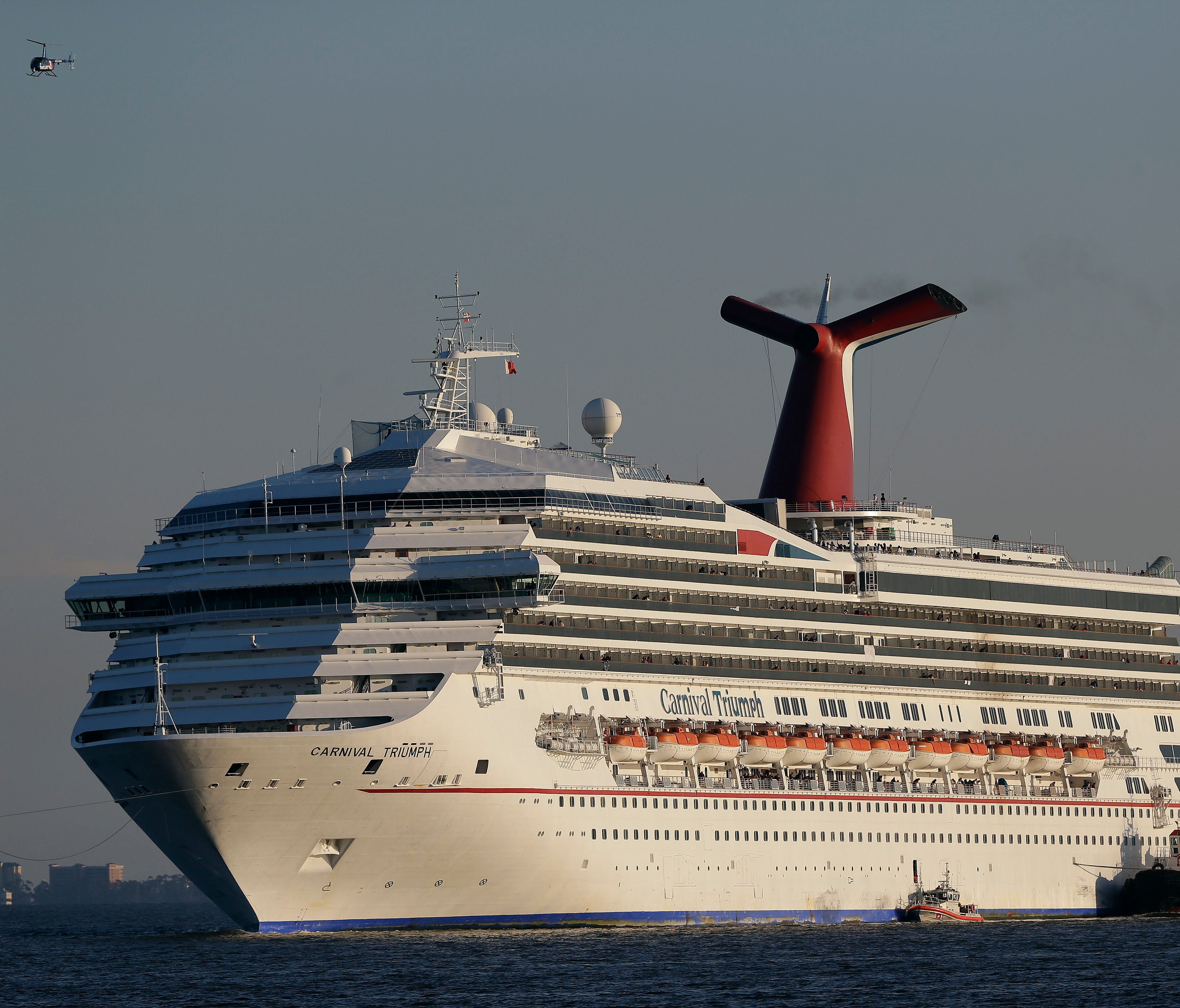 The cruise ship Carnival Triumph is towed into Mobile Bay near Dauphin Island, Ala. Feb. 12, 2013. About three dozen passengers aboard the ill-fated cruise liner have filed a lawsuit in Miami  hoping to collect thousands of dollars as a result of lin