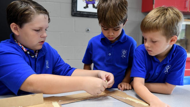 Jackson Christian 4th grader Lucas Witherspoon helps kindergartners TUcker Ragon and Jackson Voorhees with creating a solar oven during class, Monday, Aug. 21. The students are learning about the solar eclipse and how the sun works.