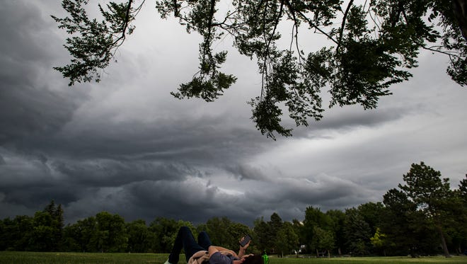 Local Brennen Crippen lounges under a tree as storm clouds build on Tuesday, June 19, 2018, at City Park in Fort Collins, Colo.