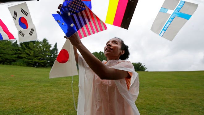 Ketrina Wonmaly from Indonesia and now a student in Appleton helps hang flags of countries at August's Celebrate Diversity picnic in Appleton's Memorial Park.
