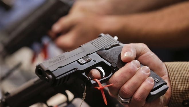 A convention attendee handles a Sig Sauer P220 .45 caliber semiautomatic pistol at the SHOT Show, Tuesday, Jan. 15, 2013, in Las Vegas.