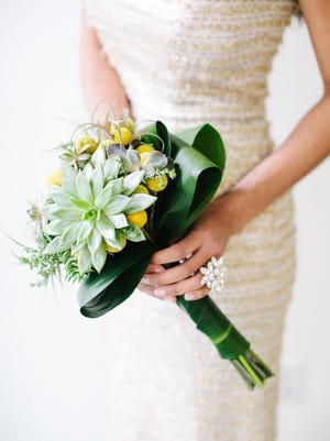 This photo provided by Hollychappleflowers.com shows shows a bouquet focused around a large, rosette-shaped echeveria succulent and secured with plant leaves, designed by Holly Chapple. Succulents are showing up everywhere in the world of weddings, from bouquets and boutonnieres to centerpieces and even take-home favors. They’re dainty yet hardy, and come in a surprising array of colors and textures. (Katie Stoops Photography/Hollychappleflowers.com via AP)