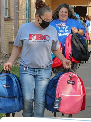 Chrystal Garman, an Elder at First Baptist Church, along with Kara Marlow, Fellowship Leader/Media-Marketing and Audio-Visual coordinator at Higher Praise Church, carry out the first of 150 backpacks on Saturday.