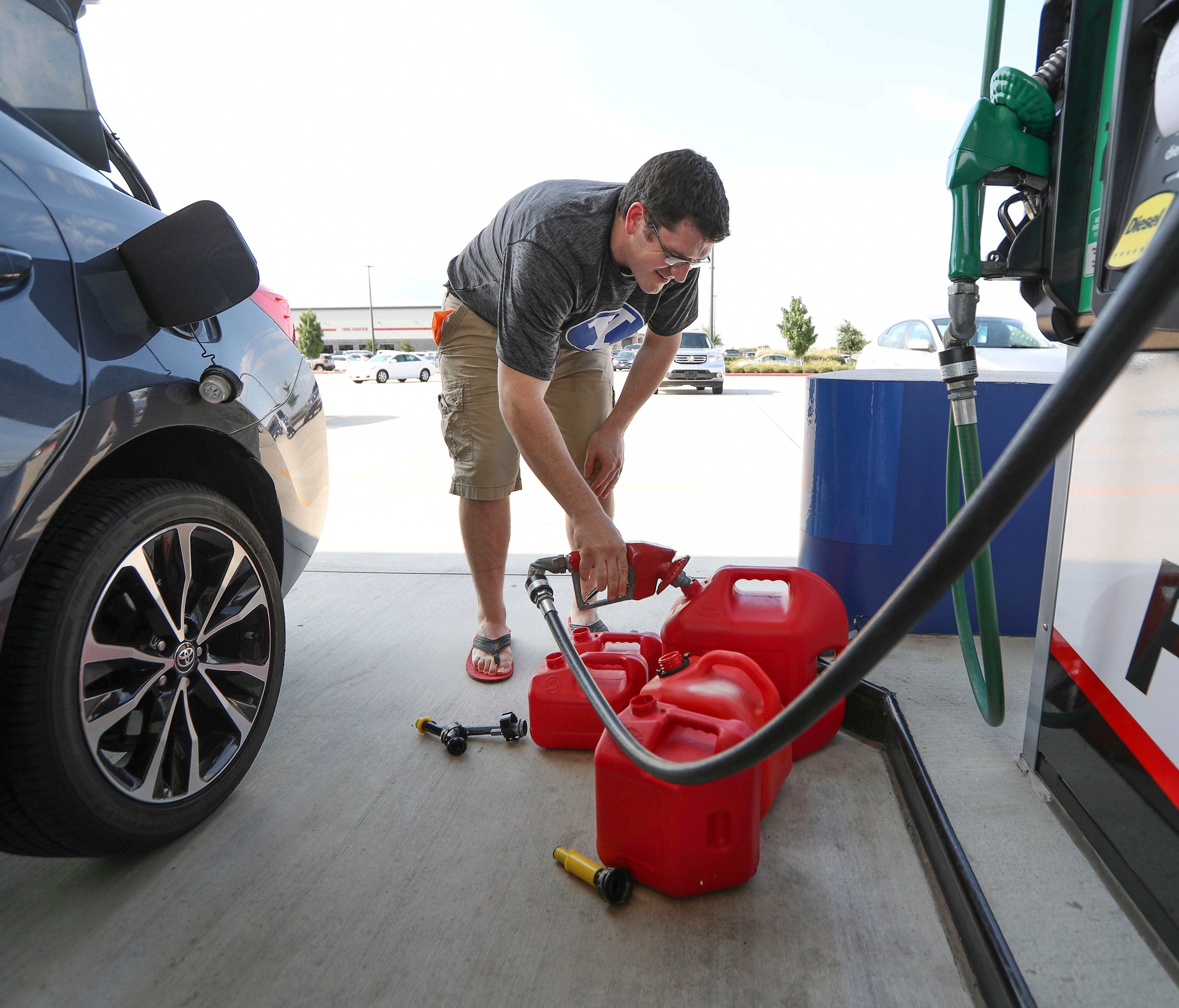 Chris Mathew fills his vehicle and five gas cans at Costco in preparation for tropical weather on Wednesday, Aug. 23, 2017, in Pearland, Texas.