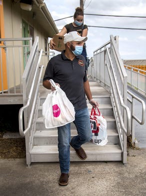 Community coordinator for Austin Voices, Jose Carrasco, carries food to the car of parent of two, Alma Vargas, at Dobie Middle School in Austin on Friday, May 8, 2020. Carrasco holds weekly food pantries for families in need as the coronavirus pandemic continues to keep schools closed.