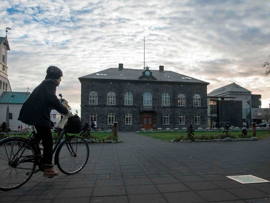 A woman bicycles past the Althingi Parliament building