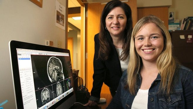 Markie Pasternak from De Pere, a senior at Marquette University (foreground), discovered with help from psychology professor Kristy Nielson (rear), that she has superior autobiographical memory, a rare condition that allows her to remember details from every day of her life. The computer shows images of her brain.