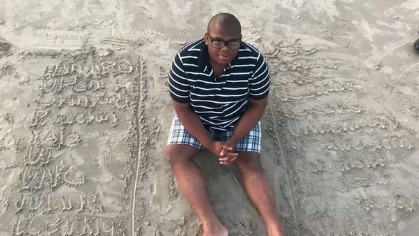 Micheal Brown, 17, sits in the sand next to the...
