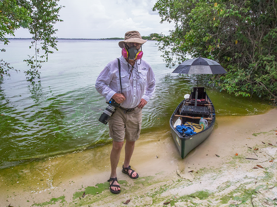 John Moran uses a respirator on the banks of the algae-choked