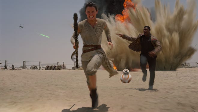 Rey (Daisy Ridley, left), BB-8 and Finn (John Boyega) hightail it in "Star Wars: The Force Awakens."