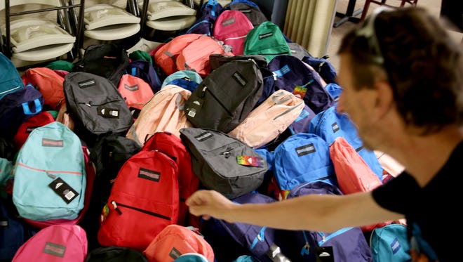 Jim Knaup, of Lebanon, drops a full backpack on the finished pile as volunteers fill backpacks with school supplies at the Salem Elks Lodge 336 on Sunday, Aug. 5, 2018.