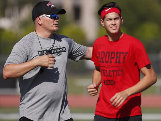Brophy Prep's Jalen Kitna walks past his father and head coach Jon Kitna watching the players warm up at Brophy Prep's field in Phoenix, Ariz. on April 23, 2018.