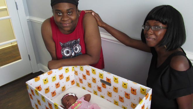 New mother Linda Wynn, left with her newborn daughter, Elizabeth Denise Gordon, in her baby box and 'Doula' Keda Henderson.