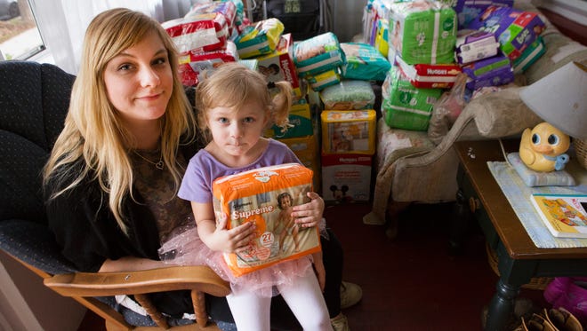 ROC City Bottoms Founder Christina Foster and her daughter, Sadie, sit on their front porch in front of a large pile of diaper and wipe donations from the Democrat and Chronicle diaper drive.