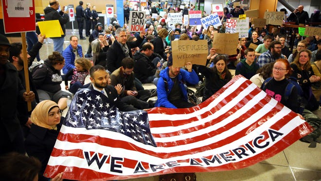 2017 AP YEAR END PHOTOS - Demonstrators sit in the concourse at Seattle-Tacoma International Airport in Seattle, Wash., with a sign that reads "We are America," on Jan. 28, 2017, as more than 1,000 people gather to protest the order signed the day before by President Donald Trump that restricts immigration to the U.S. President Trump's executive order banned legal U.S. residents and visa-holders from seven Muslim-majority nations from entering the U.S. for 90 days and put an indefinite hold on a program to resettle Syrian refugees. (Genna Martin/seattlepi.com via AP)