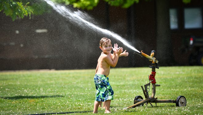 Joren McCurdy plays in a sprinkler at Lake Lansing Park South, Thursday afternoon, June 28, 2018, in Ingham County. An "excessive heat watch" will be in effect for much of southwest and south-central lower Michigan, including the Lansing area, from noon Friday through Saturday night, the National Weather Service says.