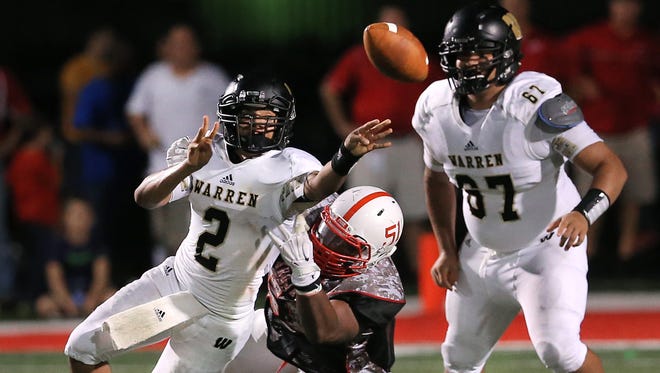 Warren Central quarterback Jordan Leach dishes off a shovel pass as he avoids being sacked by Center Grove's Sam Steimel in the second half of the season opener held at Center Grove High School on Friday, August 22, 2014. Warren Central won 12-9 in overtime.