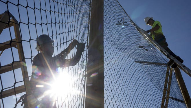 Arturo Hernandez (left) and Andres Hernandez install stainless steel mesh, August 3, 2015, on the new tiger habitat under construction at the Phoenix Zoo.