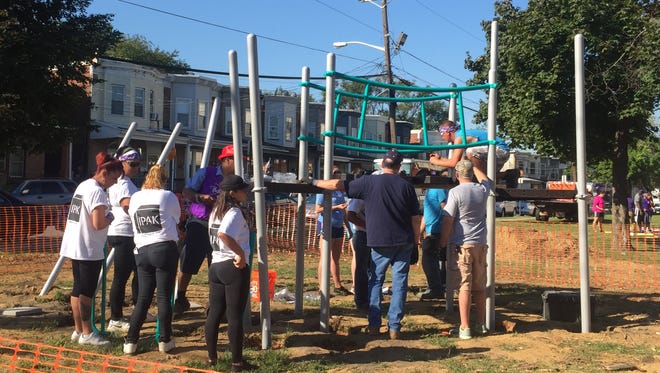 Volunteers work to build playground equipment at Whitman Park in Camden.