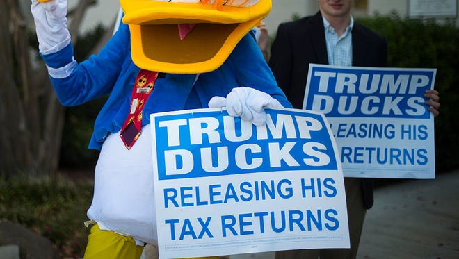 A protester dress like Donald Duck hands out "Trump Ducks" while protesting Republican presidential nominee Donald Trump's lack of tax returns released to the public outside the Republican National Committee headquarters in Washington, DC, September 13, 2016. / AFP / JIM WATSON        (Photo credit should read JIM WATSON/AFP/Getty Images)