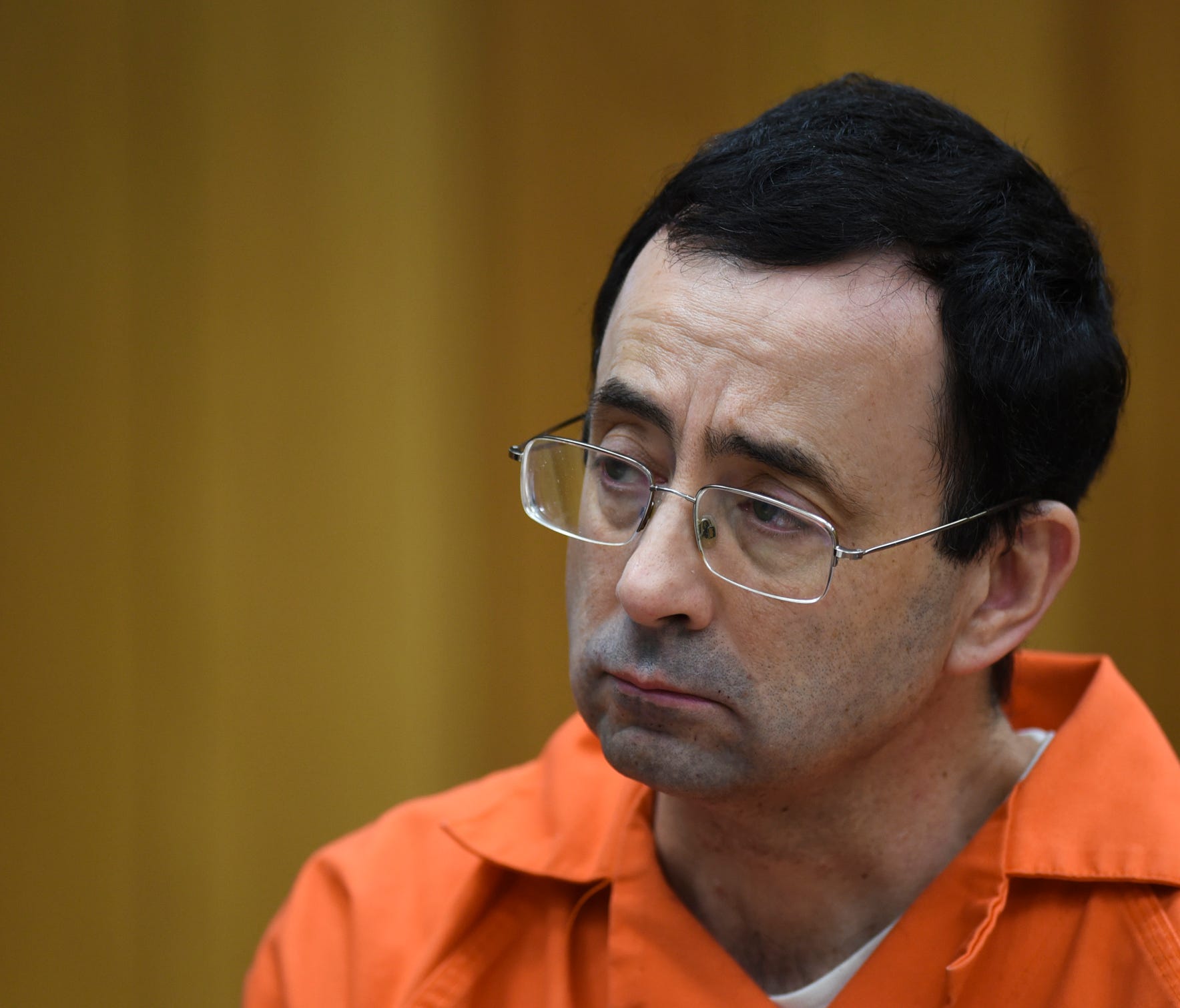 Larry Nassar listens as Rachael Denhollander gives her victim impact statement Friday, Feb. 2, 2018, in Eaton County Circuit Court, the second and final day of victim impact statements in Judge Janice Cunningham's courtroom in Charlotte, Mich.   He w