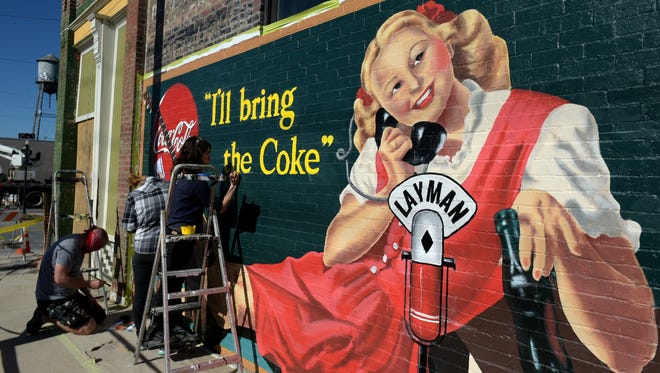 Mural artist Michael Cooper and his crew paint a new 1930s retro Coca Cola mural on the side of the Historic Layman Drug Co. building in Chestnut Hill. Restoration of Layman Drug Company building is in progress and  will become a commercial recording space when finished.