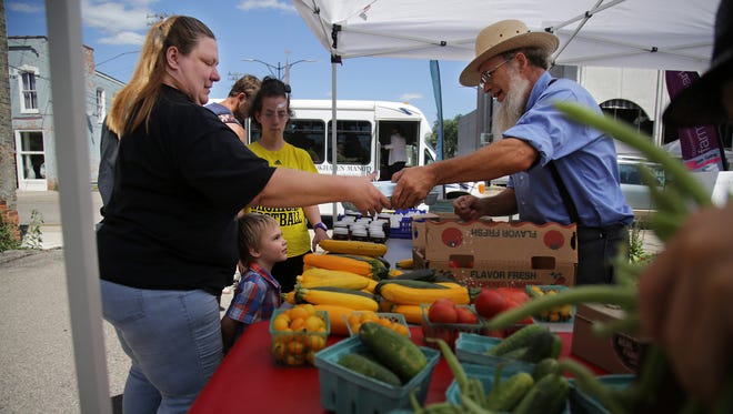 April Petraska of Ypsilanti receives tokens from Roberta Reed, 42, of Ypsilanti that she can use to purchase fruits and vegetables at the farmers market in Ypsilanti. Her doctor gave her a prescription for produce.