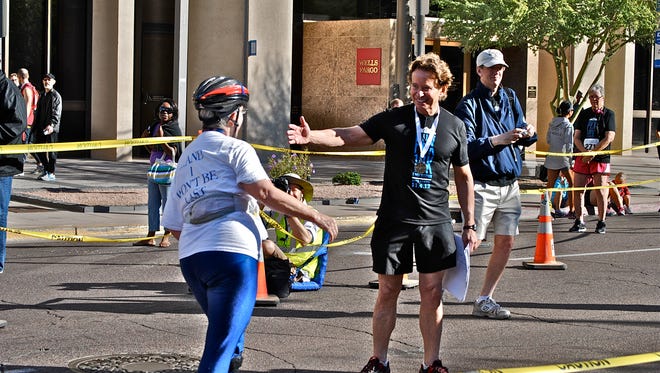 Sally Whitney comes to the finish line being greeted by Dr. Art Mollen, founder of the Phoenix 10K & Half-Marathon.