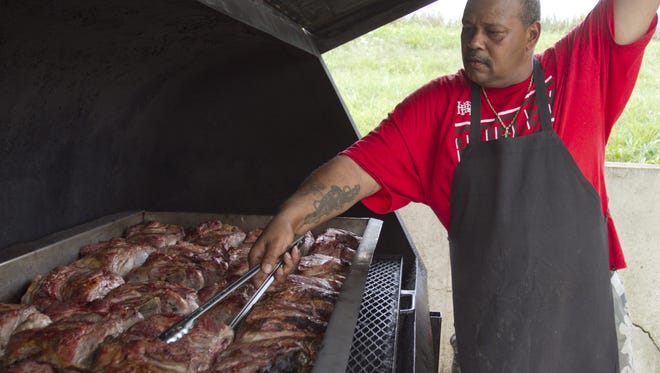 Hog Wild Bar BBQ pitmaster David Price flips pork shoulder on his outdoor grill in this September 2015 photograph. Hog Wild has since closed.