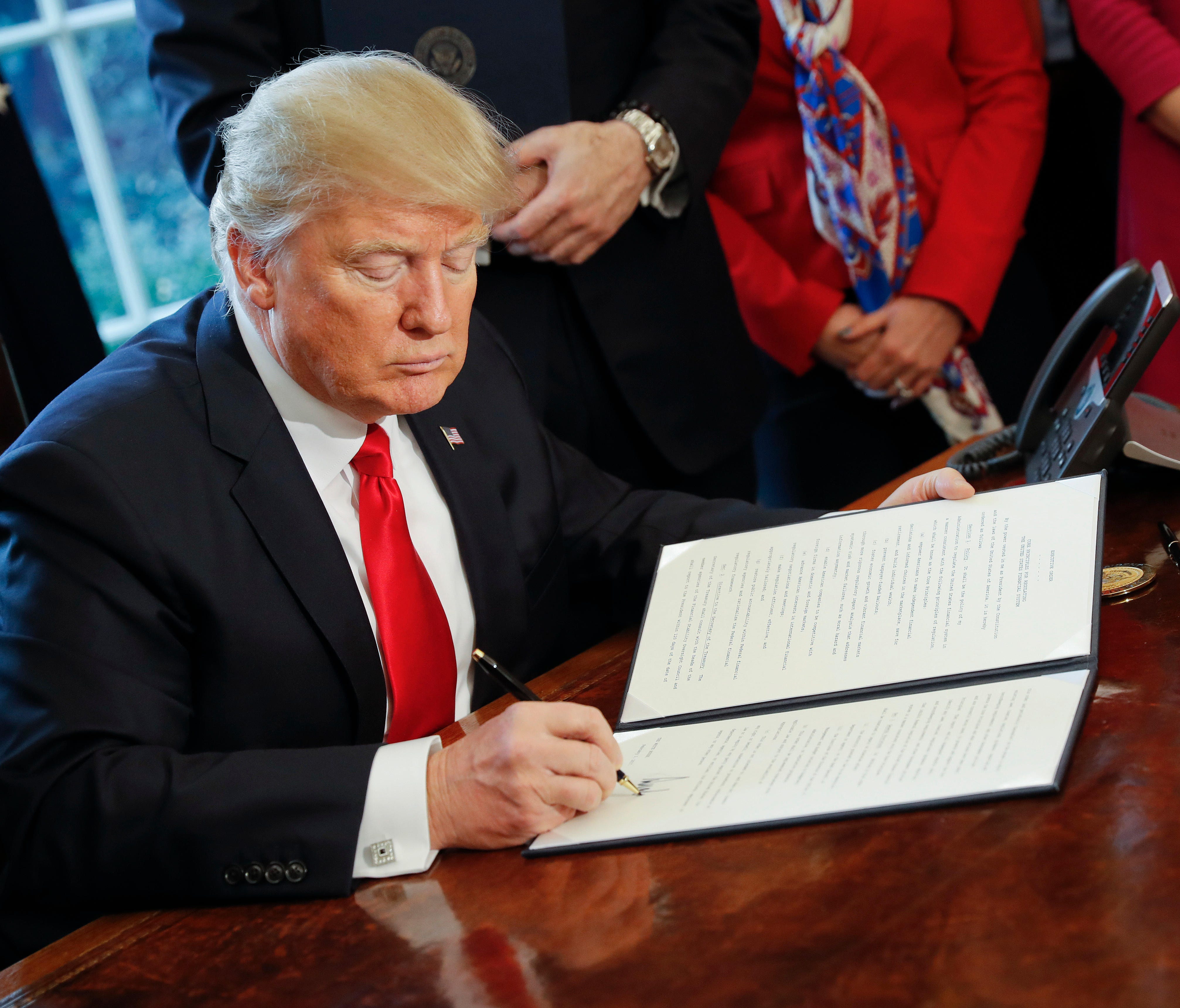 President Trump signs an executive order in the Oval Office on Feb. 3.