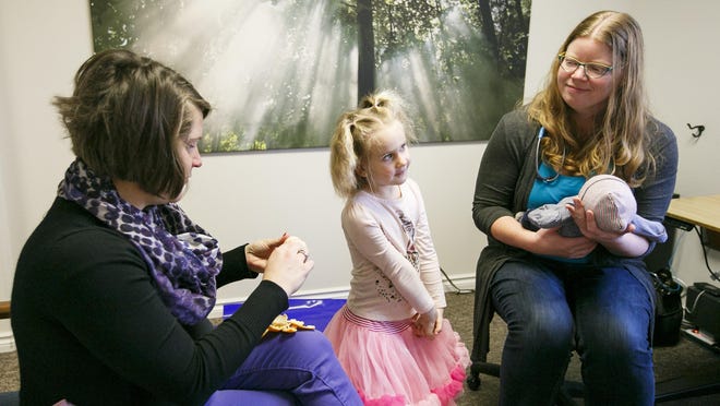 Erin Wood peels an orange while Lucy Wood, 5, looks at Dr. Lara Knudsen, holding two-week-old William Wood. Knudsen runs the clinic herself, and the small practice means she can spend more time with her patients and even make house calls.