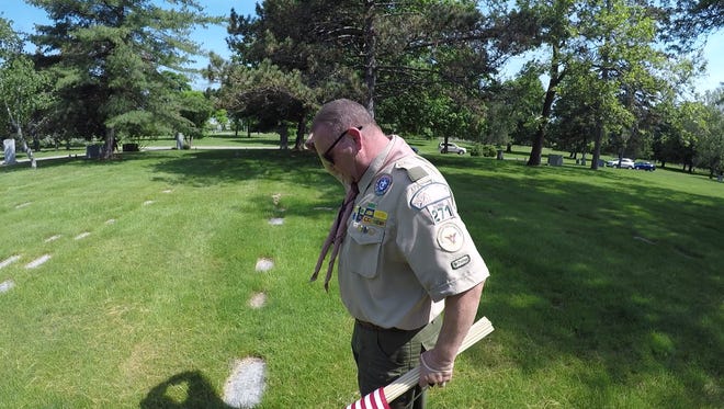 Troop 271 Assistant Scoutmaster Dave Hedman salutes after putting a flag on a grave at Holy Sepulchre Cemetery in Southfield. Troop 271 spent Memorial Day decorating the graves of veterans with American flags.