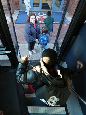 Students getting off of the school bus at Cochran Elementary are greeted by Americorps volunteer Rachel Lacer.  The Americorps program, in several JCPS schools, is called REACH. It aims to reduce chronic absenteeism in younger students by having a dedicated Americorps volunteer working as mentors to students who have been identified as chronically absent.