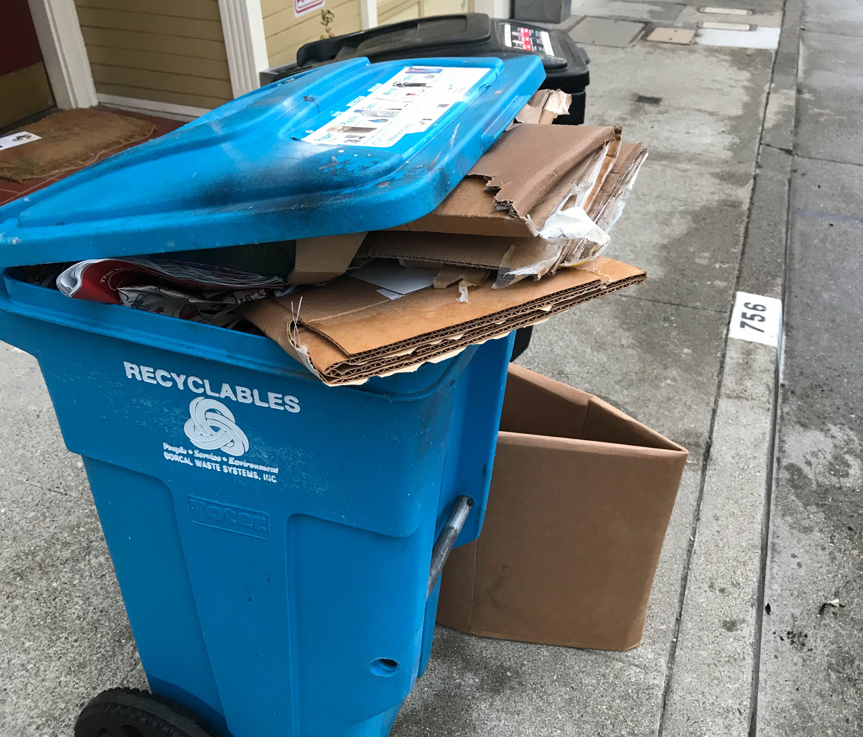 A recycling bin overflows with corrugated cardboard boxes.