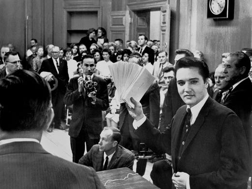 More than 150 people jammed into the mayor's office Dec. 17, 1963, to see Elvis Presley hand out Christmas checks totaling $55,000. The checks benefited 58 Memphis and Mid-South charities. In appreciation, the organizations presented Elvis with a six-foot plaque. It was warm in the room, and when Commissioner Claude Armour announced Elvis was going to pass out the checks, the singer wiped his brow and said, 'Elvis is going to pass out, period.'