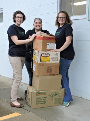 Left to right, Stacy Goodhue, library director; Peggy Hugen, vice president of Friends of the Carlisle Library; and Kristin Johnson, president, take a breather while hauling books for the upcoming sale.