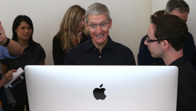 Apple CEO Tim Cook looks at the new 27 inch iMac with 5K retina display during an Apple special event on Oct. 16 in Cupertino, Calif.